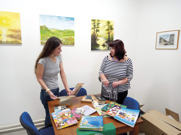 Iniciátorka projektu Markéta Řeřichová (vlevo) přebírá shromážděné knižní dary od Renaty Bartákové, vedoucí MěK Uhlířské Janovice (Foto: Robert Neradil)